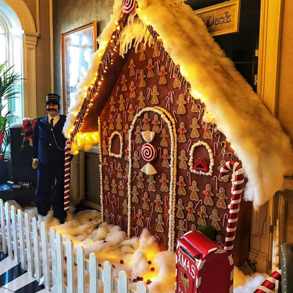 a gingerbread house with lights and a man standing in front of it