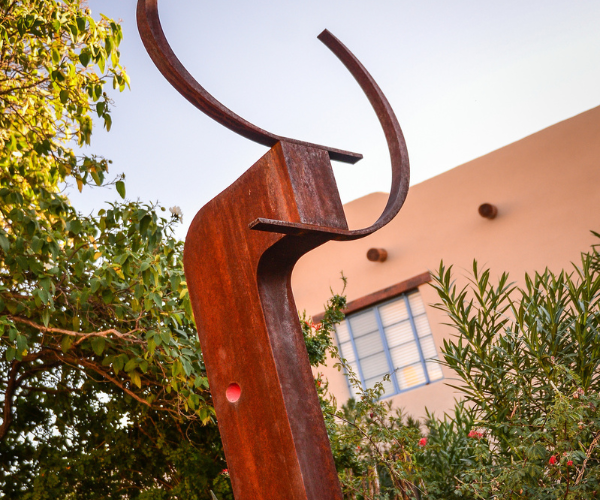 a sculpture outside with trees and a building in the background