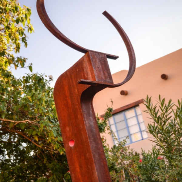 a sculpture outside with trees and a building in the background
