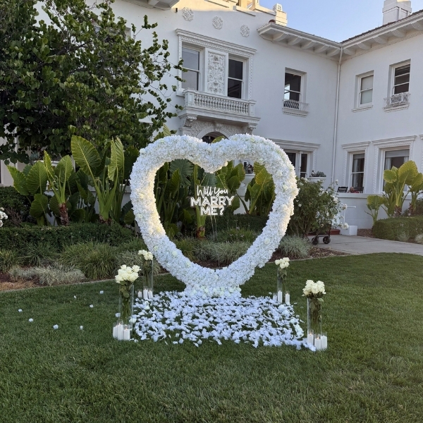a heart shaped flower arrangement in front of a white building