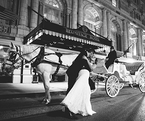 a man and woman kissing in front of a horse carriage