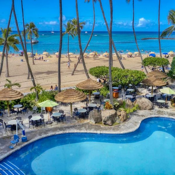a pool with umbrellas and chairs on a beach