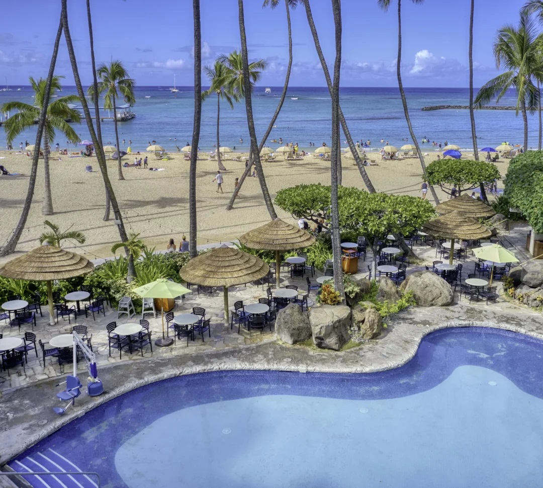 a pool with umbrellas and tables and chairs on a beach