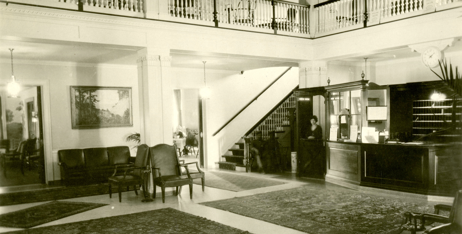 a black and white photo of a lobby with a person behind the counter