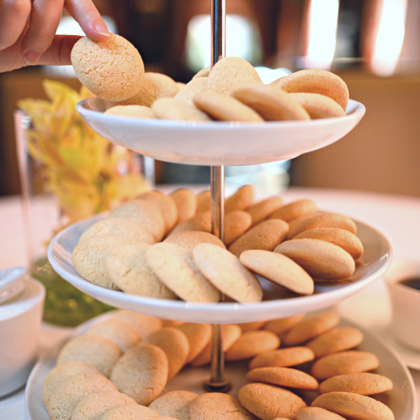 a hand reaching for a cookie on a tiered tray