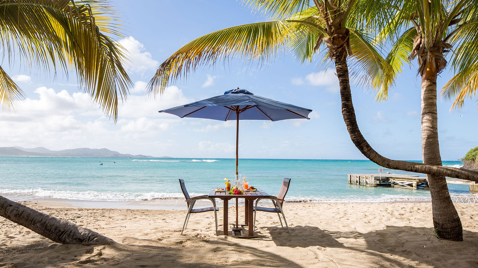 a table and chairs under an umbrella on a beach