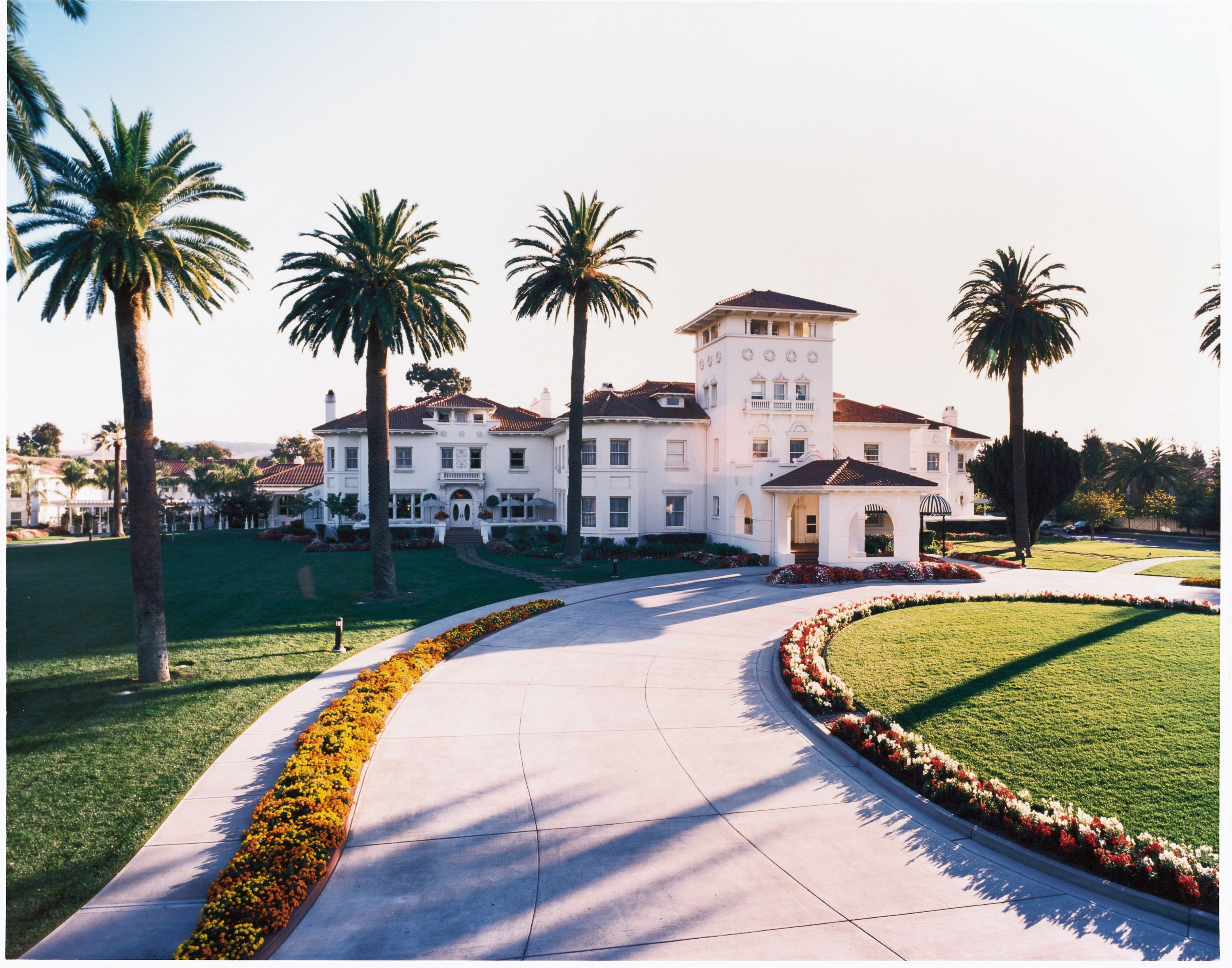 a large white house with palm trees and a lawn