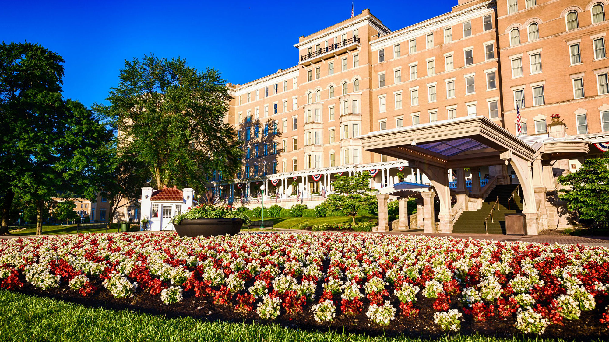 a large building with a flower bed and a lawn 0