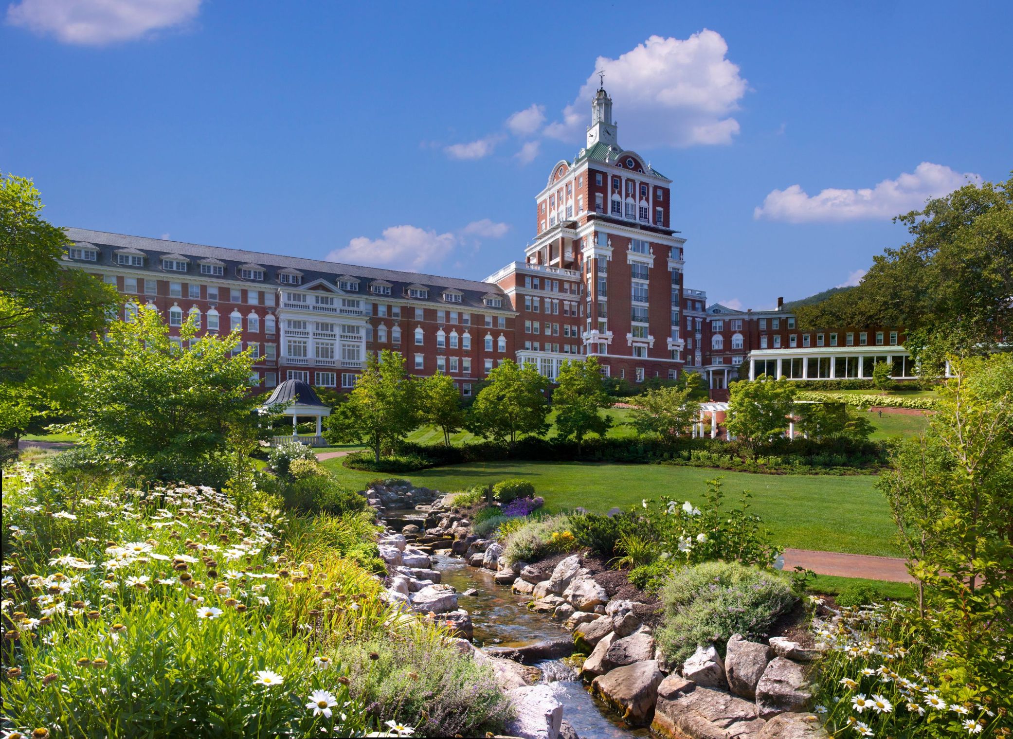 a large building with a stream in front of it with The Homestead in the background