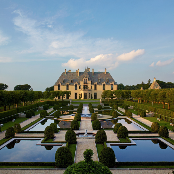 a large formal garden with water fountains and hedges with Vaux-le-Vicomte in the background