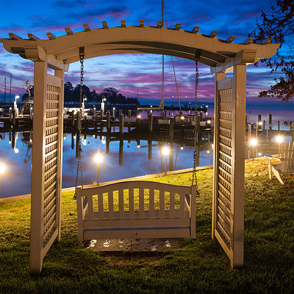 a wooden swing with lights on the water
