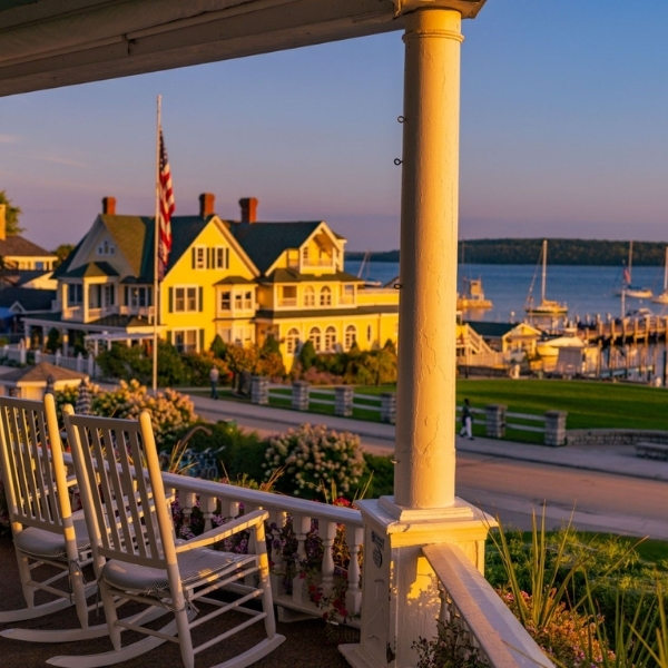a white rocking chairs on a porch overlooking a waterfront