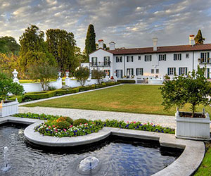 a large white house with a pond and a lawn