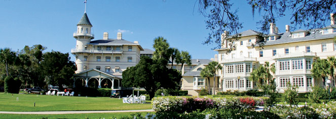 a large white building with a lawn and trees