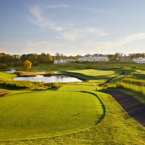 a golf course with a pond and a building in the background