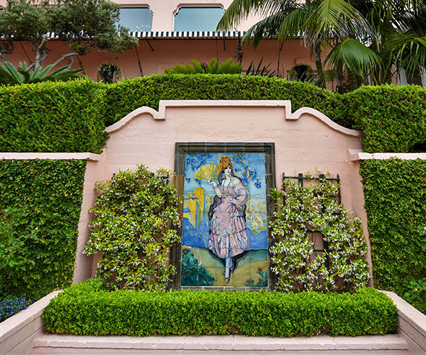 a painting on a wall with bushes around it