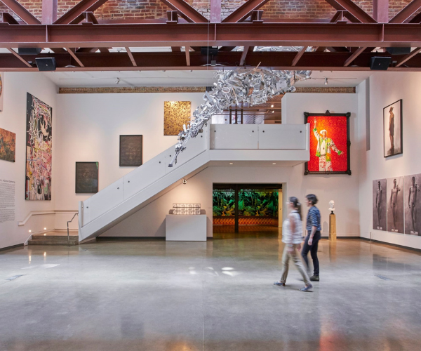 a couple of people walking in a room with art on the wall