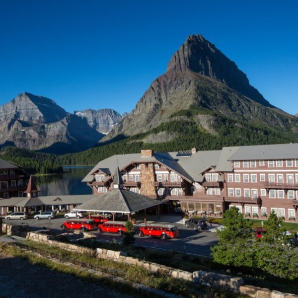 a hotel with red buses parked in front of mountains