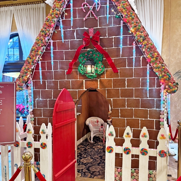 a gingerbread house with a door and a white fence