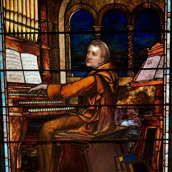 a stained glass window with a man playing the piano