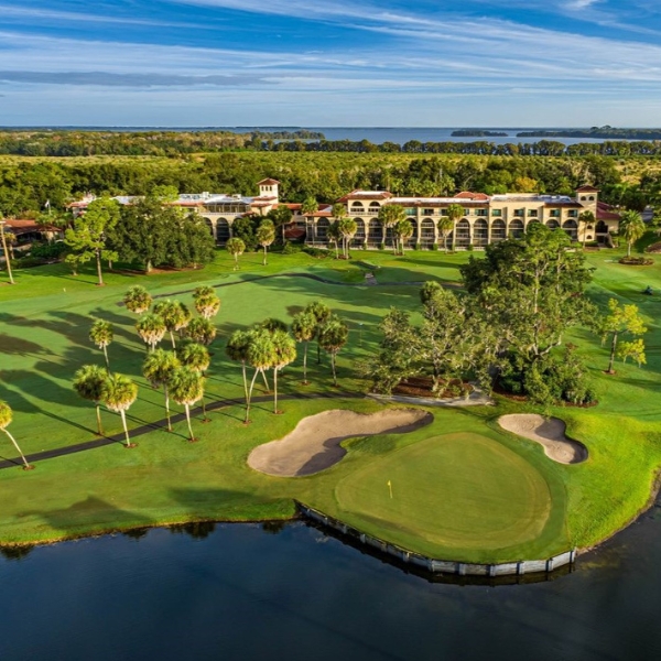 a golf course with a large building and a body of water