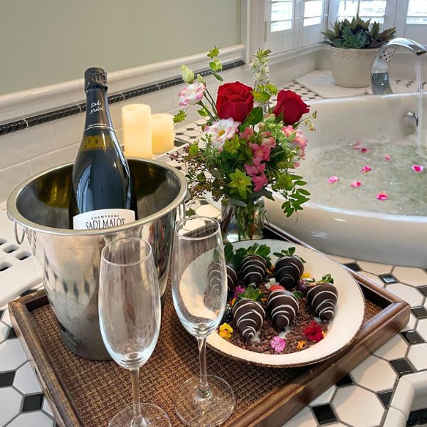a champagne bottle in a bucket and a bowl of chocolates and flowers
