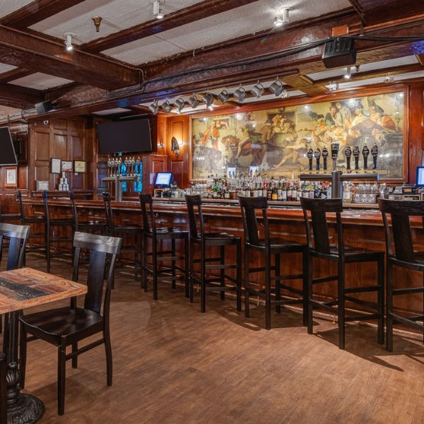 a bar with a row of chairs and a wall of beer
