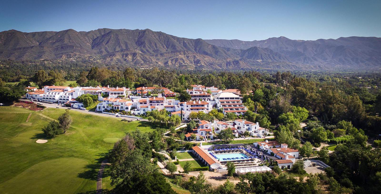 a large white building with a pool in front of a large mountain