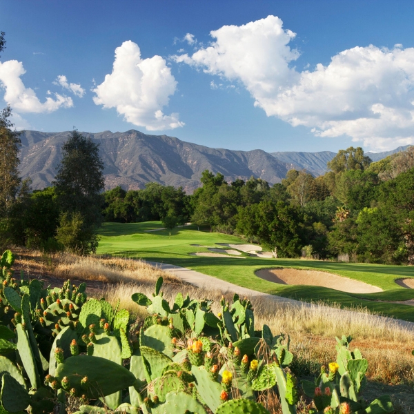 a golf course with cactuses and mountains in the background