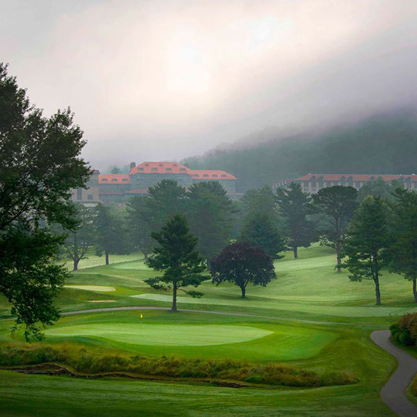 a golf course with trees and a building in the background