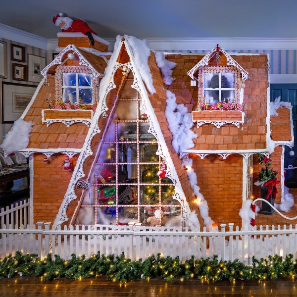 a gingerbread house with lights and a fence