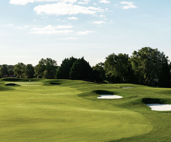 a golf course with sand bunkers and trees
