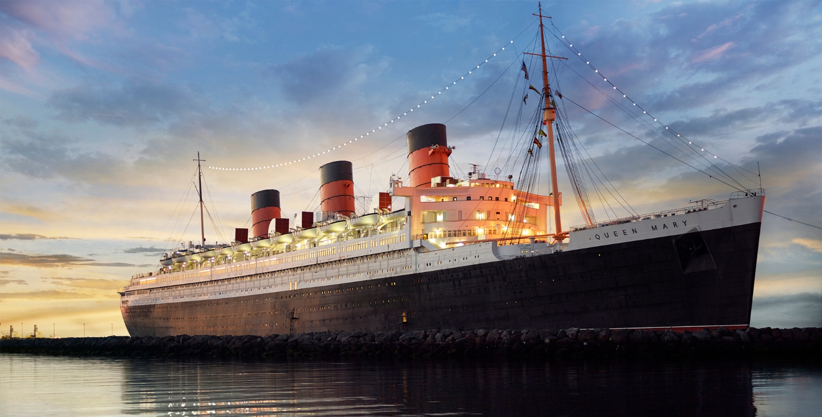a large ship on the water with RMS Queen Mary in the background