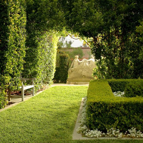 a garden with a statue and hedges