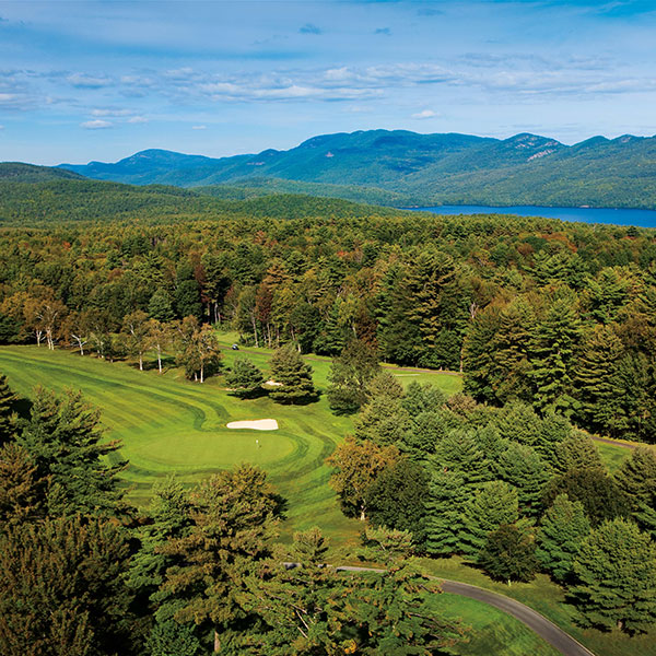 a golf course with a lake and mountains in the background