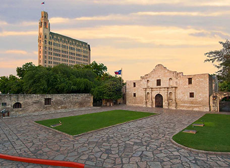 a stone courtyard with a building and trees 19