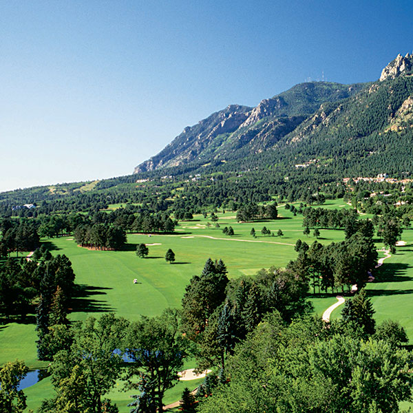 a golf course with trees and mountains in the background