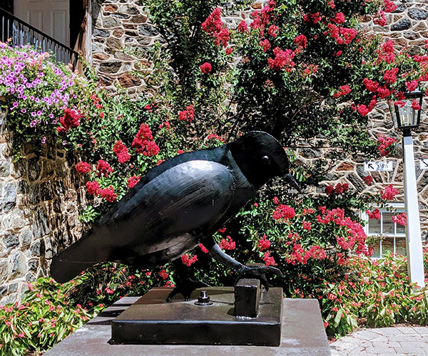 a statue of a bird on a pedestal in front of a stone building