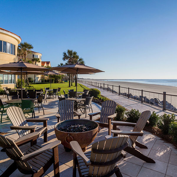 a patio with chairs and umbrellas by the beach