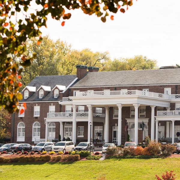 a large brick building with columns and cars parked in front of it