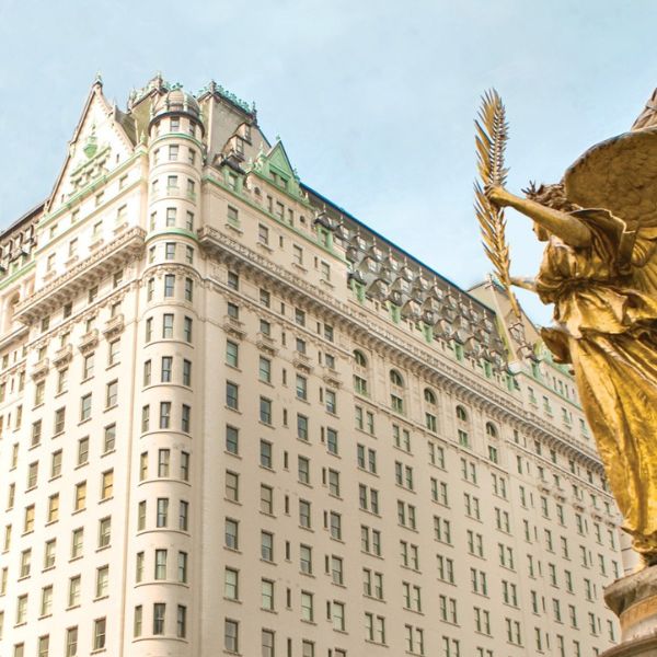 a statue of an angel holding a wheat stalk in front of a large building