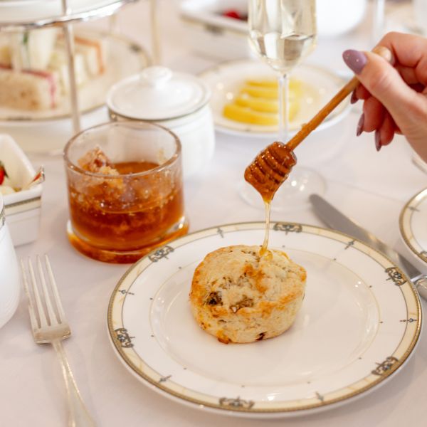 a person pouring honey onto a plate of food