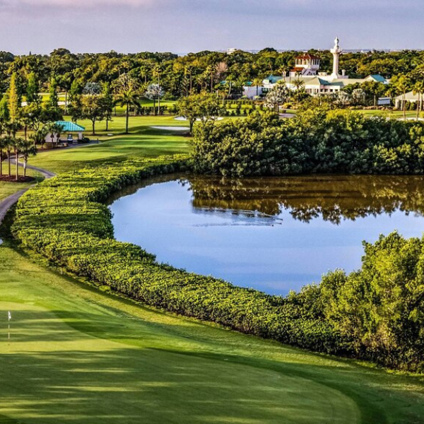 a golf course with a body of water and a building