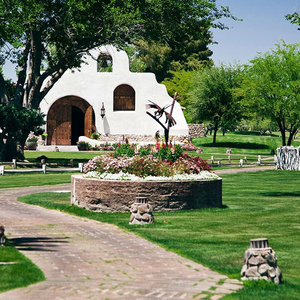 a white building with a flower bed in front of a lawn