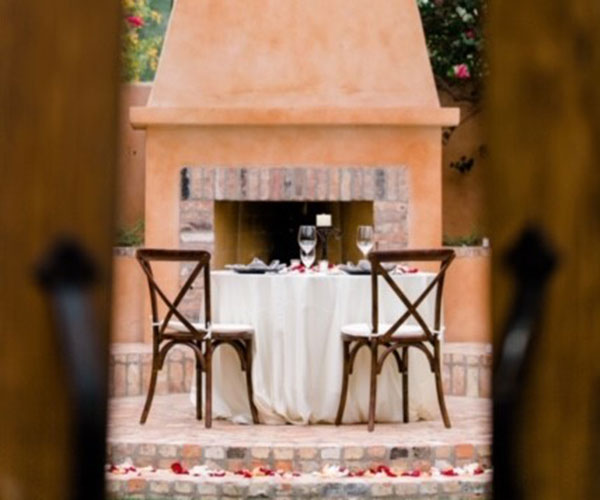 a table with wine glasses and chairs in front of a fireplace