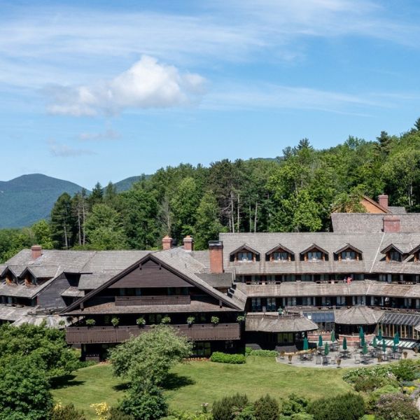 a large building with trees and mountains in the background