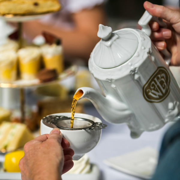 a person pouring tea into a cup