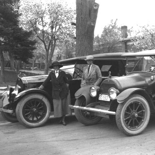 a couple of people standing next to old cars