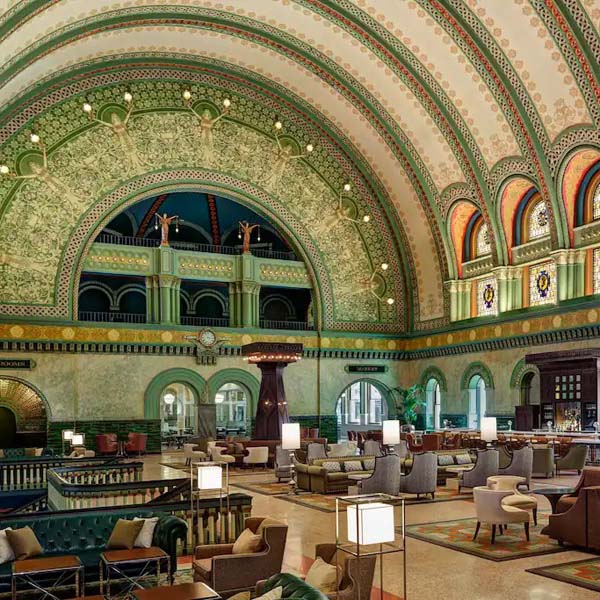 a large ornate building with many chairs and tables with Union Station in the background