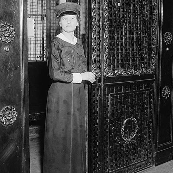 a woman in a dress and hat standing in front of a door